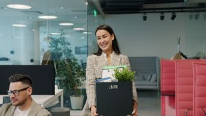 New starter arriving at an office carrying a box of desk things